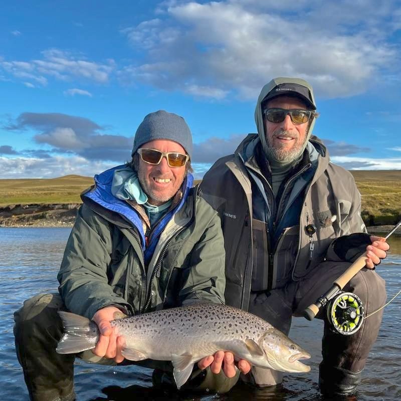 Two anglers holding a large brown trout